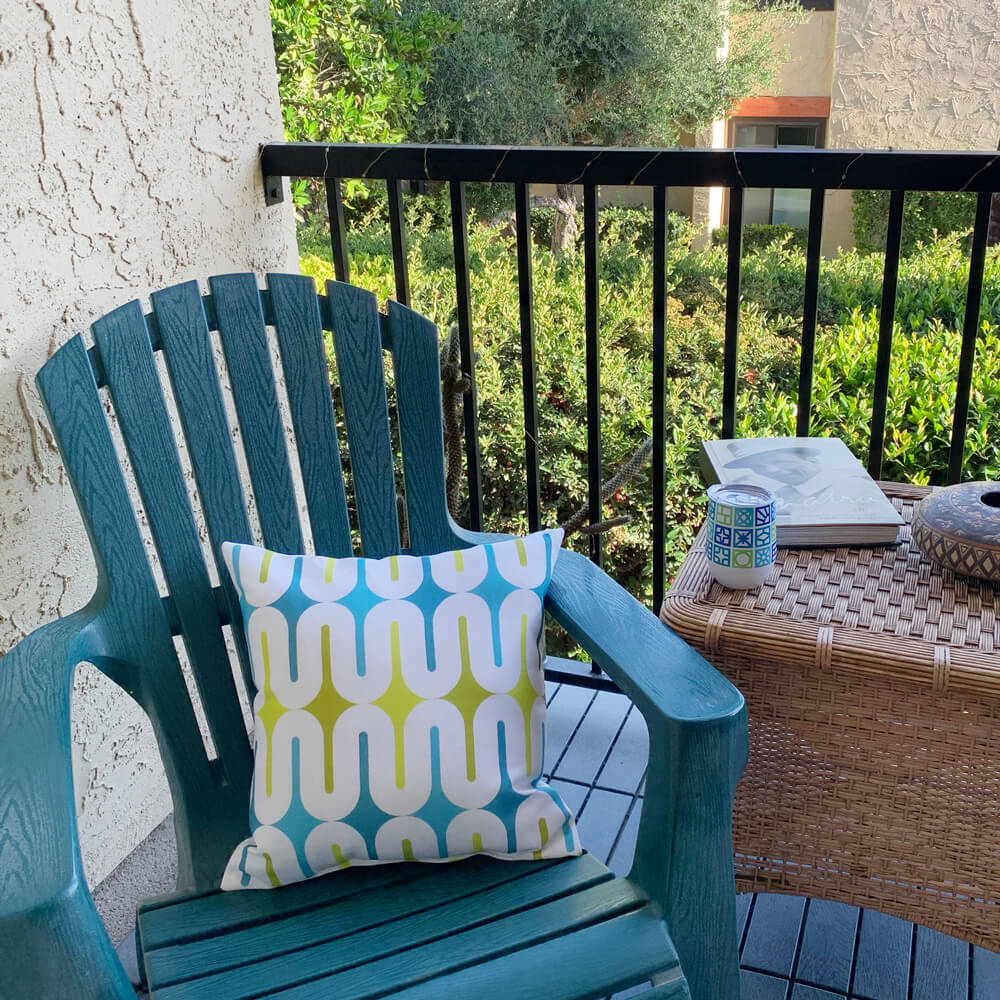 Mid Century Modern Aqua Green Galaxie 18" Outdoor Pillow on an adirondack armchair