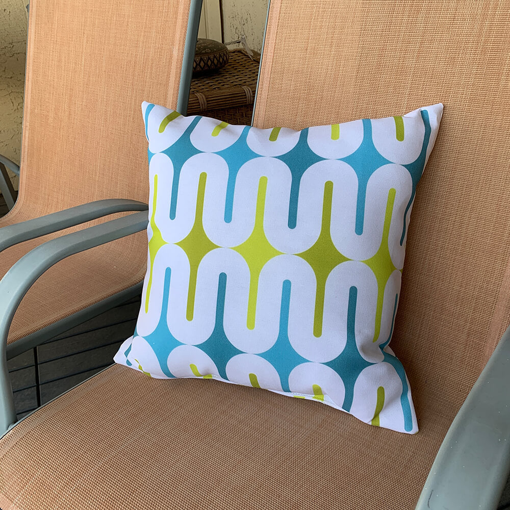 Mid Century Modern Aqua Green Galaxie 18" Outdoor Pillow on a balcony armchair