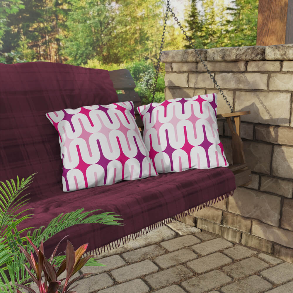 Two Mid Century Modern Pink Galaxie 18" Outdoor Pillow on a swing bench